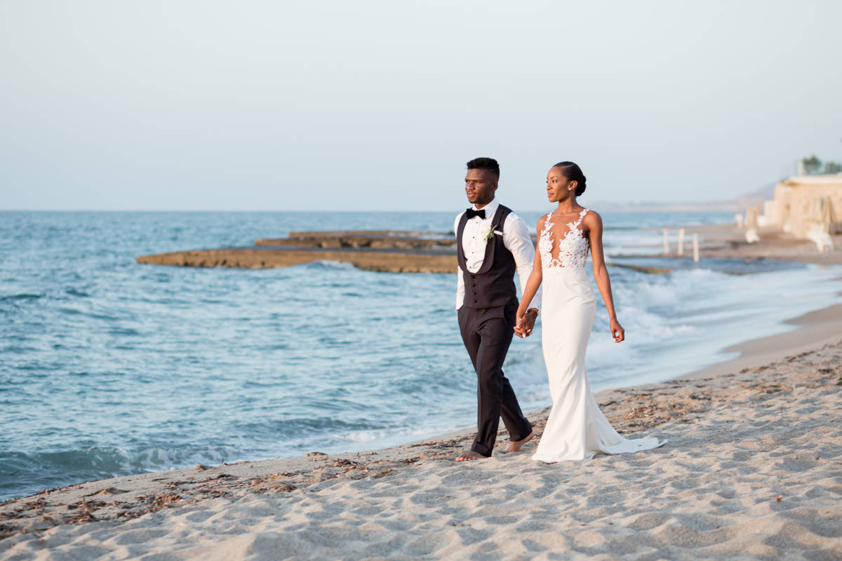 bride and groom walking by the sea during sunset